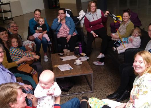 Group of women, babies and children sitting around the table.