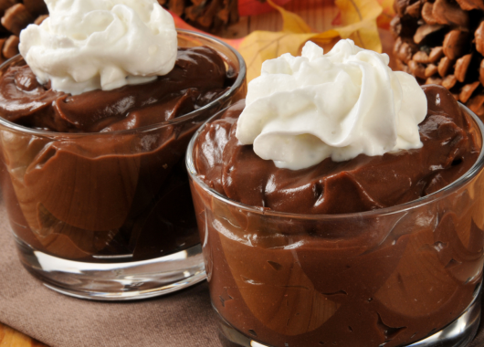 two chocolate desserts topped with whipped cream in glass