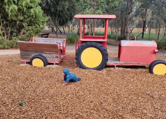 Image of a baby crawling near a play tractor.