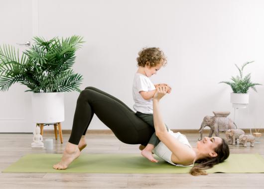 Mother on a yoga mat exercising with her toddler