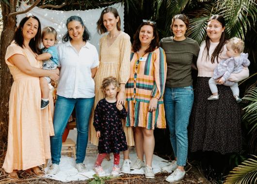 6 Tarragindi Group volunteers standing in a line with three children and toddlers. They are looking connected and like they are having a good time. 