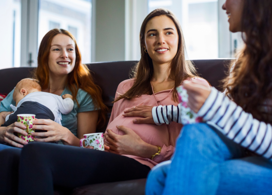 Three mums sit and chat with their babies over a cuppa