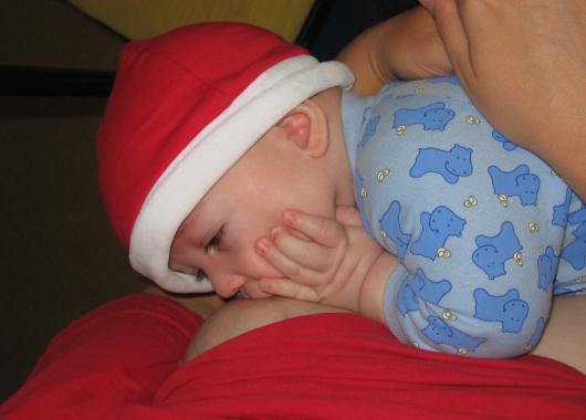 baby breastfeeding in a santa hat