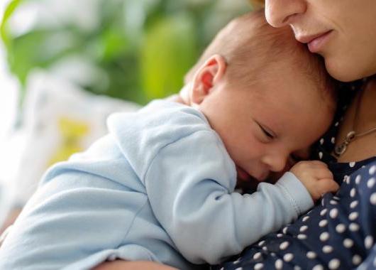 Newborn baby snuggled into it's mothers chest