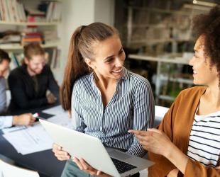 Two women in a workplace looking over a laptop