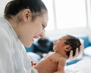 A mother smiles at her newborn baby