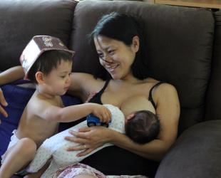 Mum feeding baby with toddler