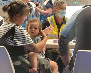 A mother with young baby waits at the registration desk of an evacuation centre during an emergency.