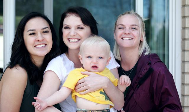 An image of three women. The middle one is holding a baby.