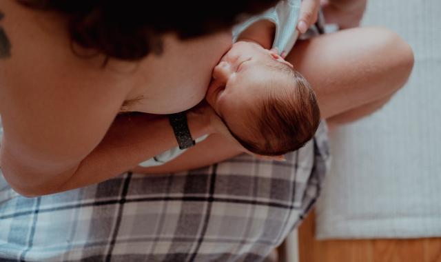 An image of a woman sitting and breastfeeding her baby.