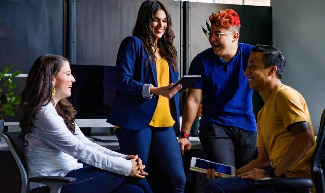 four employees discussing work ideas around a computer