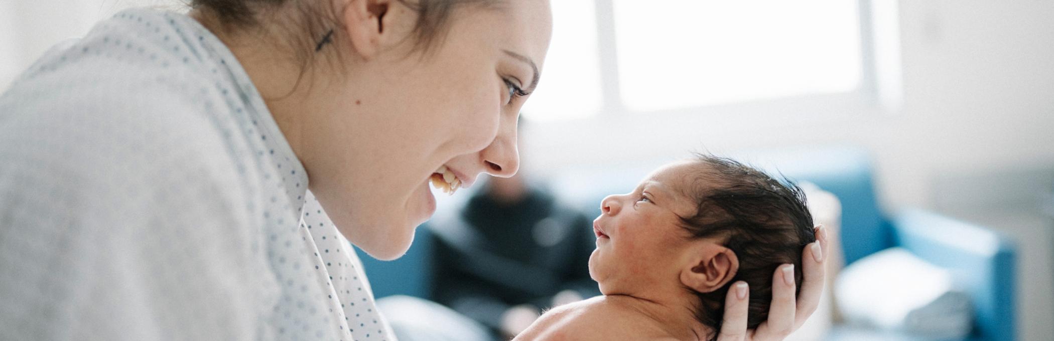 A mother smiles at her newborn baby